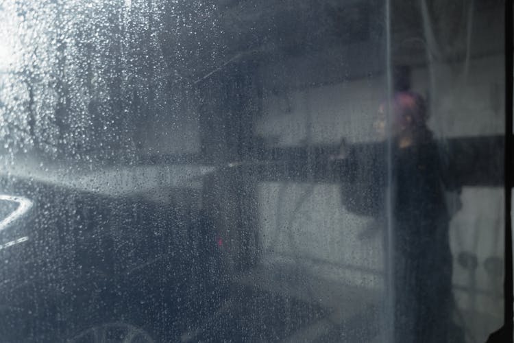 A Person Cleaning A Car Behind The Plastic Curtain