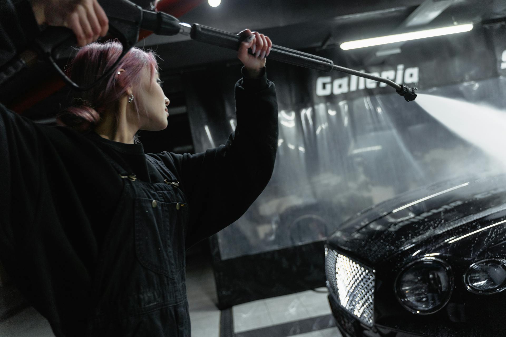 A Woman Washing a Car with a Power Spray