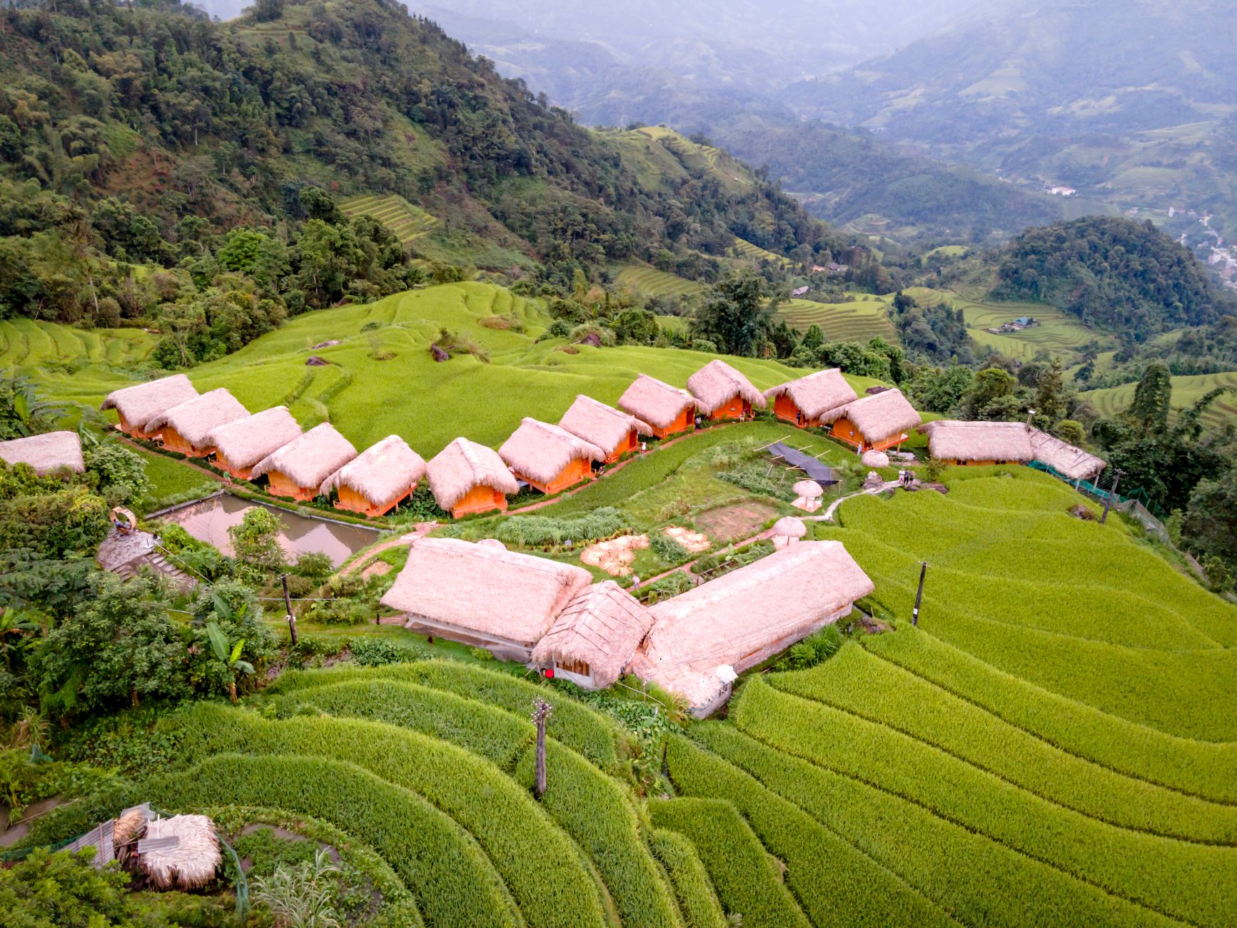 Aerial shot of Hoang Su Phi Lodge nestled in verdant rice terraces, Vietnam.