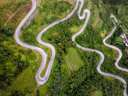 Free Stunning aerial shot of a winding road through lush green hills, showcasing a picturesque countryside setting. Stock Photo