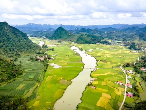 Free Aerial view showcasing a verdant valley with vibrant green fields and a winding river. Stock Photo