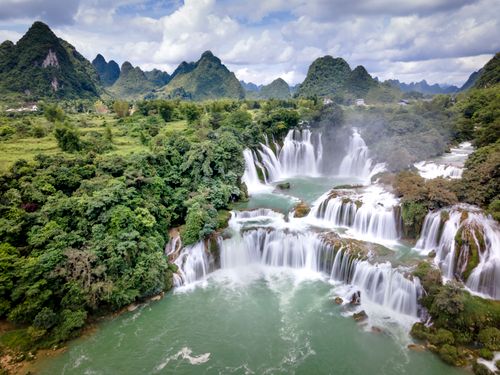 Free A breathtaking aerial view of cascading waterfalls amidst verdant mountains. Stock Photo