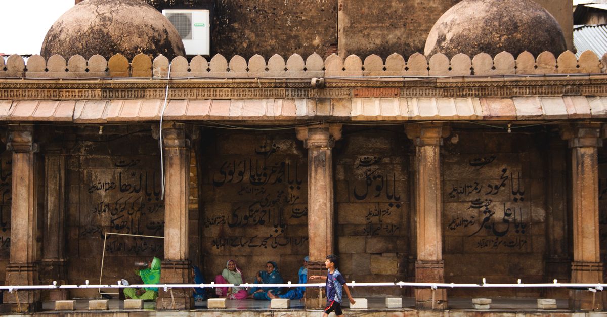 Traditional architectural arches with visitors at a temple in Ahmedabad, India showcasing cultural heritage.