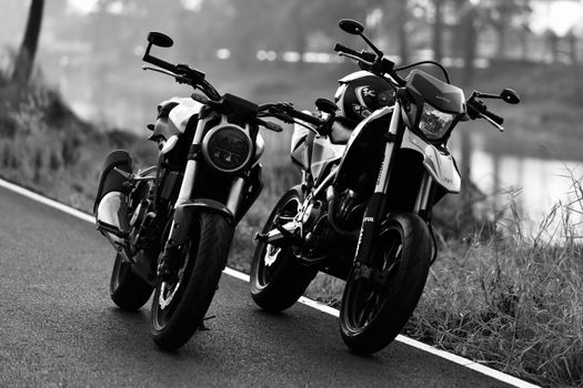 Monochrome photo of two motorcycles parked on a road, showcasing classic style and design.