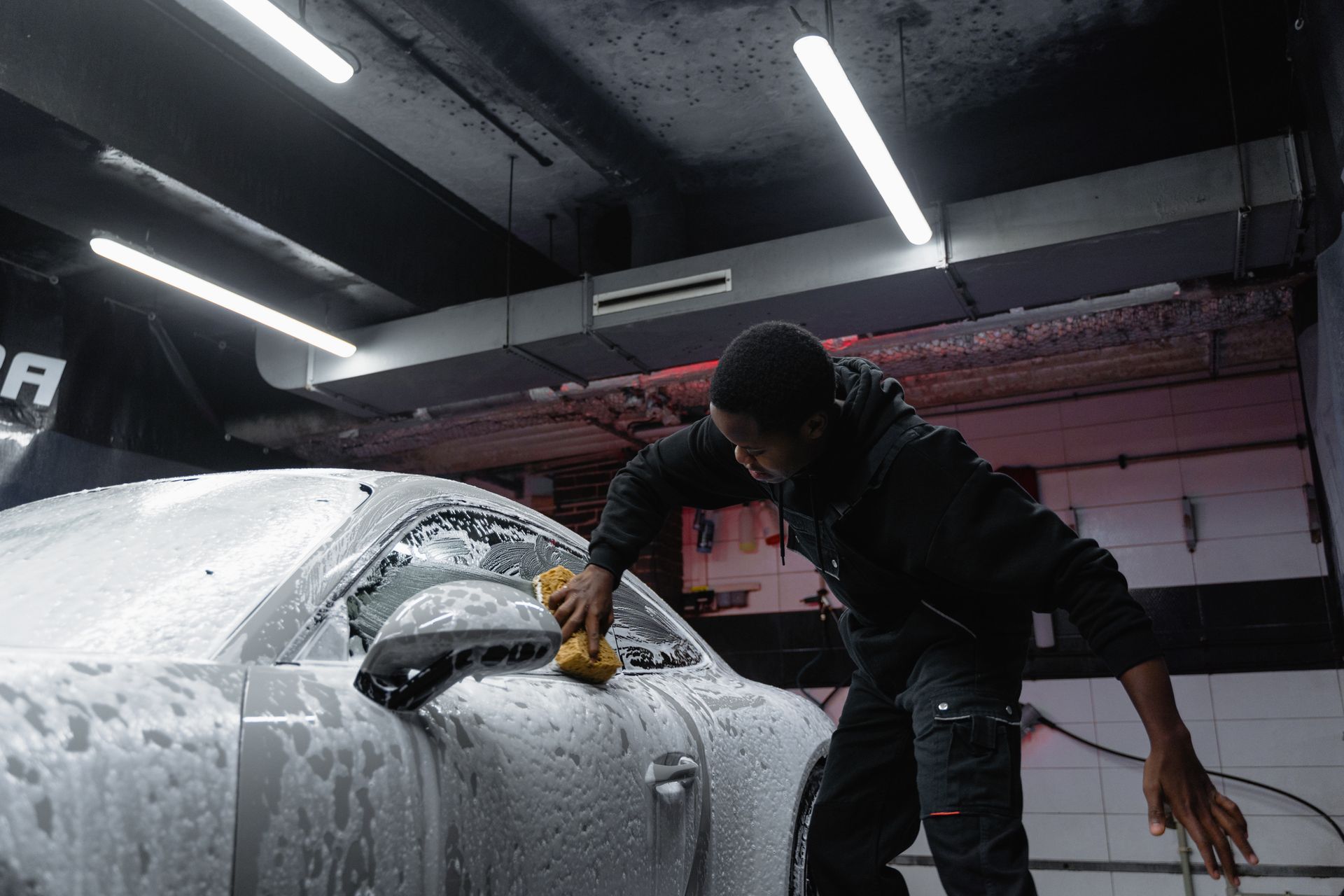 Instructor guiding a trainee polishing a car hood