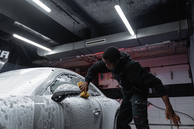 A Man Cleaning The Car With A Sponge