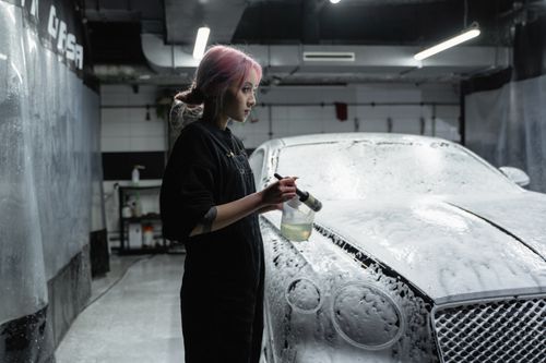 Free Asian woman washing luxury car in indoor car wash with foam. Stock Photo