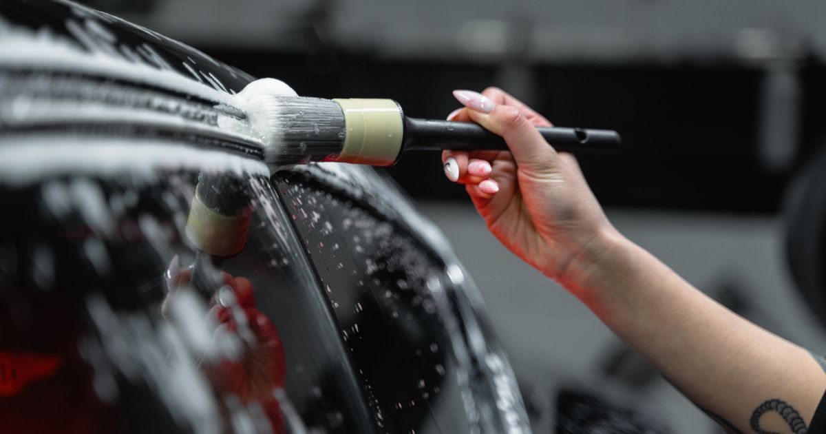 Detailing brush cleaning the painted surface of a car