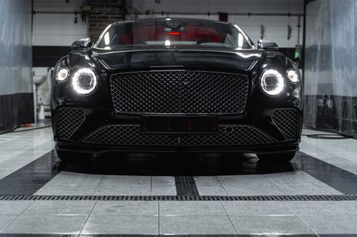 Free Front view of a sleek black Bentley inside a car wash, showcasing elegance and luxury. Stock Photo