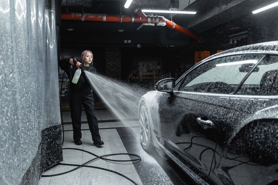 Detailer pressure washing a car