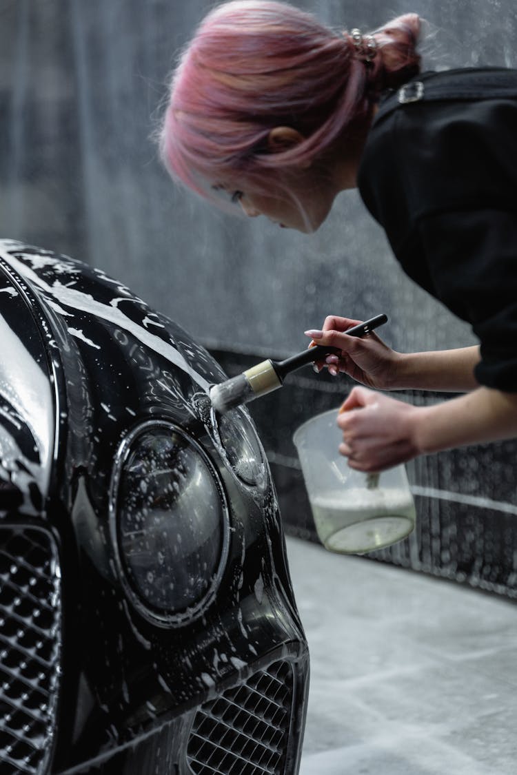 Woman Cleaning The Headlight Of A Car