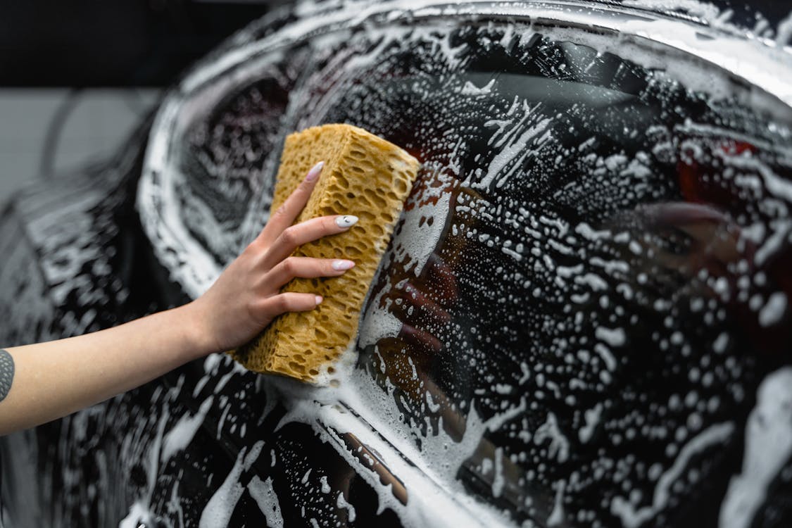 Free Photo of a Person Cleaning the Window of a Black Car Stock Photo
