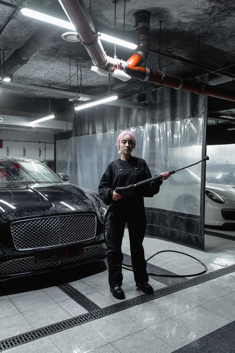 Woman Standing In Front Of A Black Car While Holding A Pressure Washer