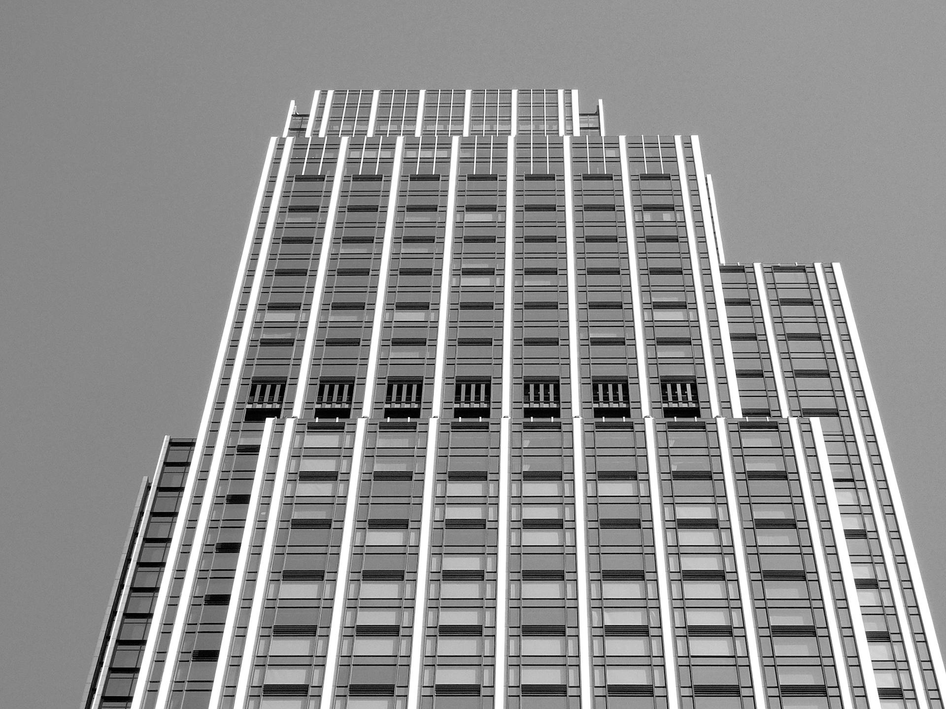 From below of black and white modern multistory commercial building with geometric facade and glass windows against cloudless sky in city