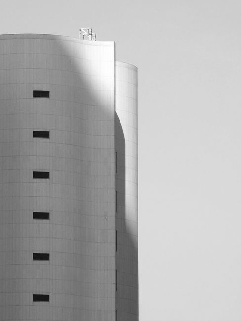 Black and white facade of modern unusual building with curvy walls and symmetric windows on sunny day