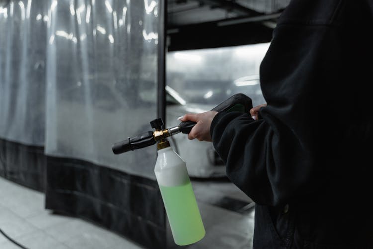 A Person In Black Jacket Holding A Spray Bottle