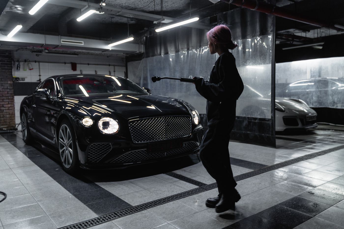 Washer hand-buffing the bonnet of a dark sedan