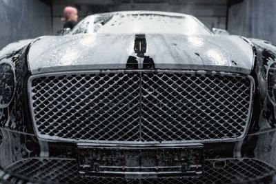 Black car covered in soap foam during a detail wash