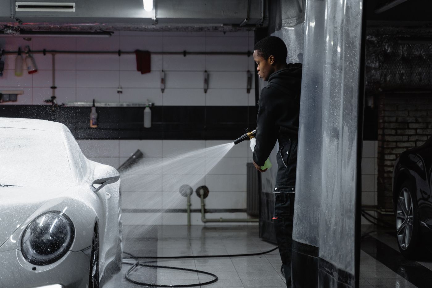 Car wash attendant pressure washing a vehicle during exterior prep
