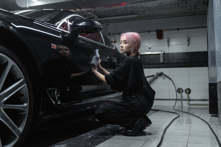 Woman In Black Sweater Wiping The Black Car