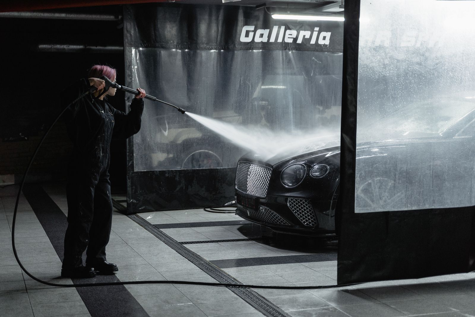 A car moving through the lit tunnel at Ultimate Express Car Wash in Layton, water and foam jets running