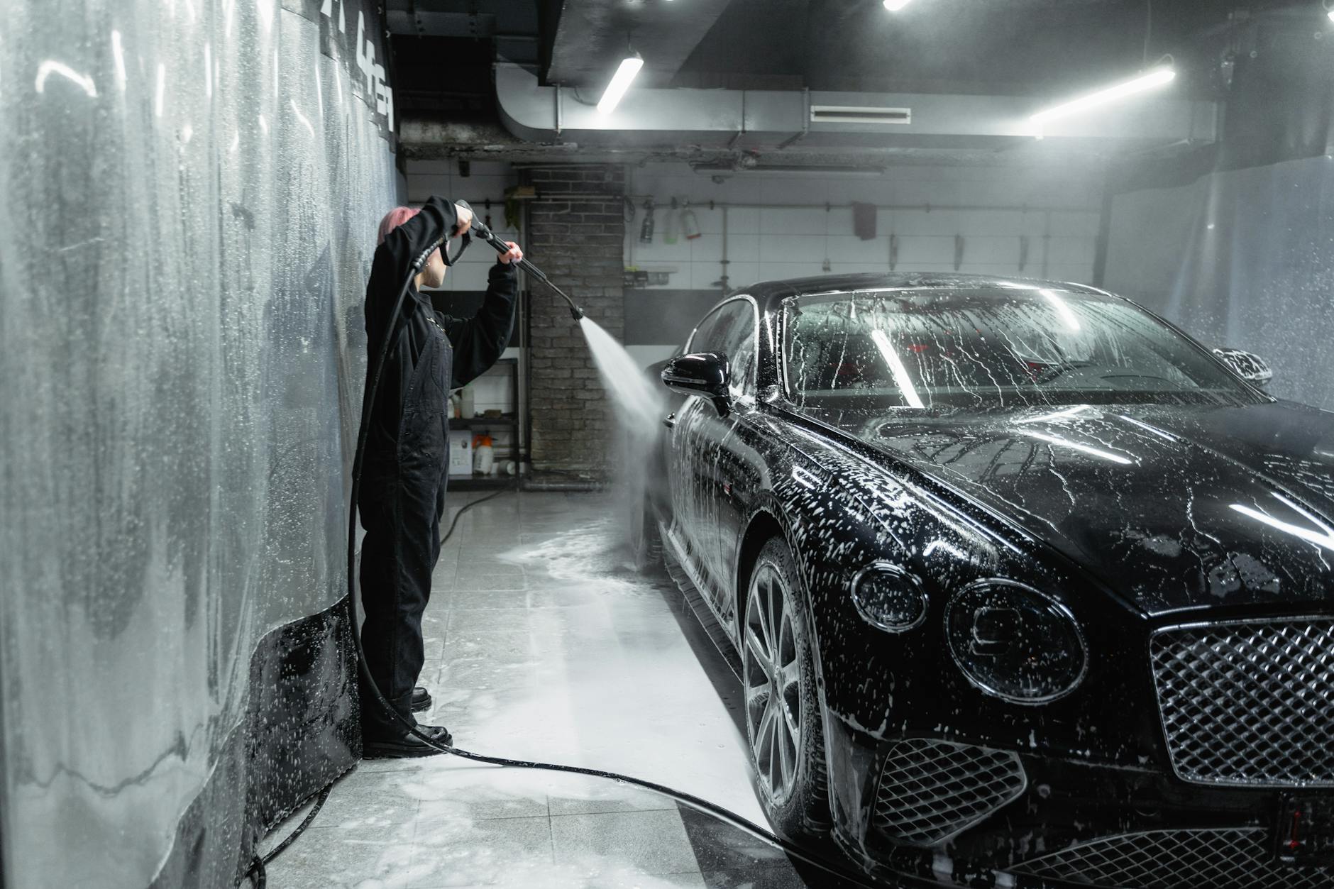Woman in Black Uniform Washing a Black car