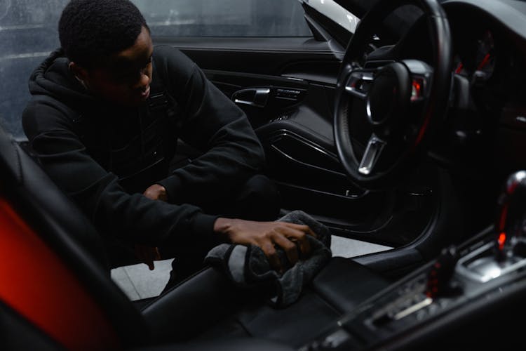 A Man In Black Jacket Cleaning The Seat Of A Car