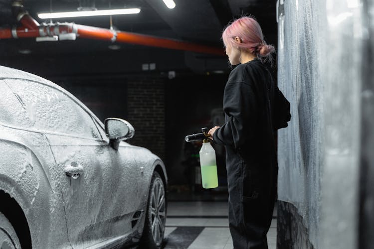 A Woman Covering A Car With Shampoo Foam