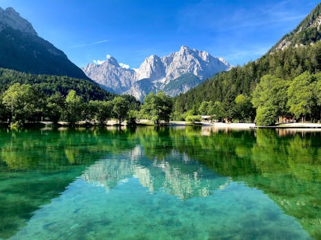 Serene landscape of Lake Jasna reflecting the Julian Alps under a clear blue sky in Slovenia.