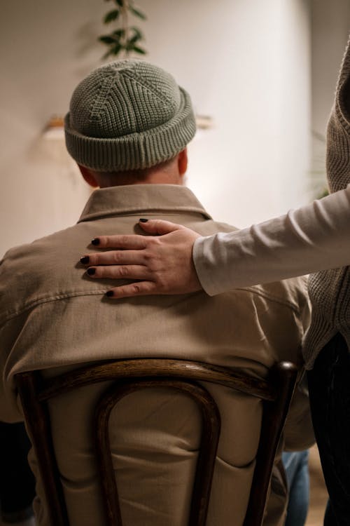 A Hand on the Back of a Person Wearing a Knit Hat