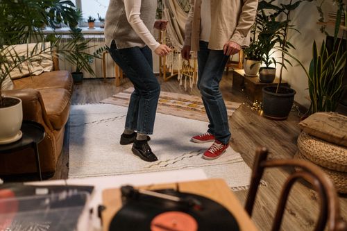 Free Two adults dancing casually in a cozy indoor living room with vinyl records and houseplants around. Stock Photo