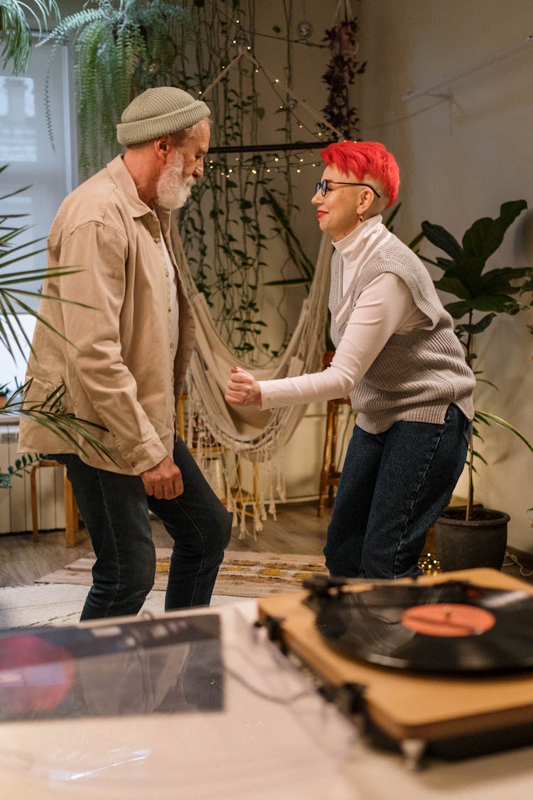 An Elderly Couple Dancing To The Music At Home