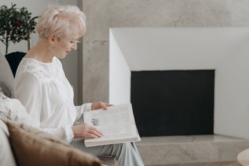 Photo of a Woman with White Hair Reading a Book