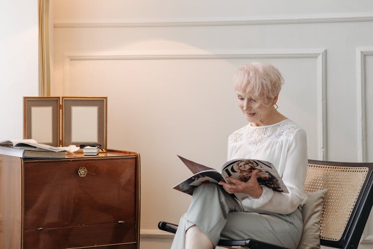 An Elderly Woman Reading A Magazine