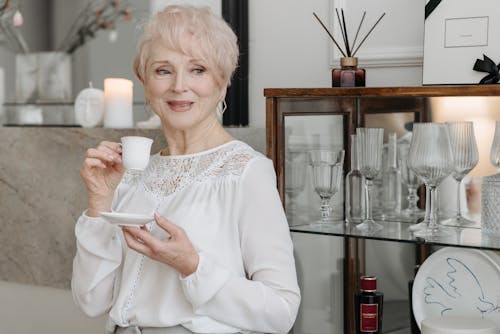 Free Photo of an Elderly Woman Holding a White Cup while Looking Away Stock Photo