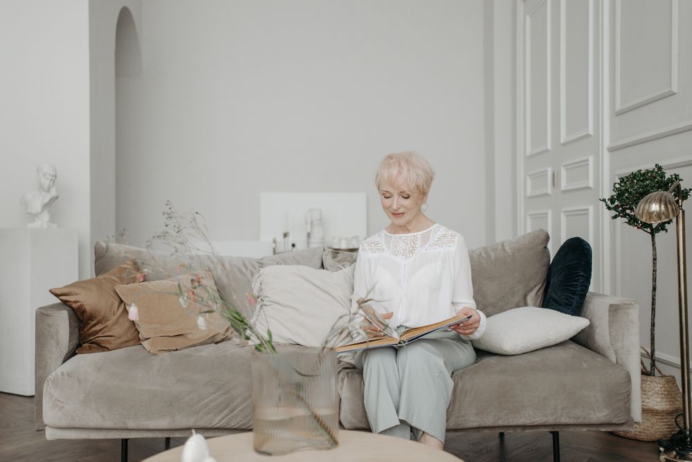 Illustrative photo of an older woman reading in a comfortable living room