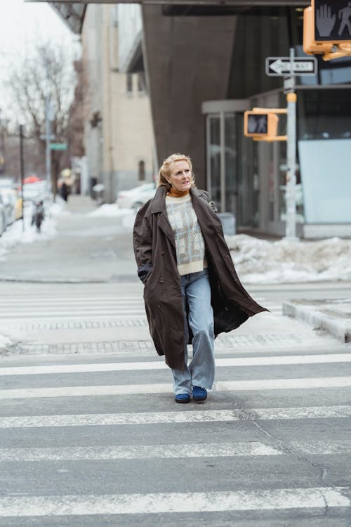 Elderly woman in coat crossing road in town