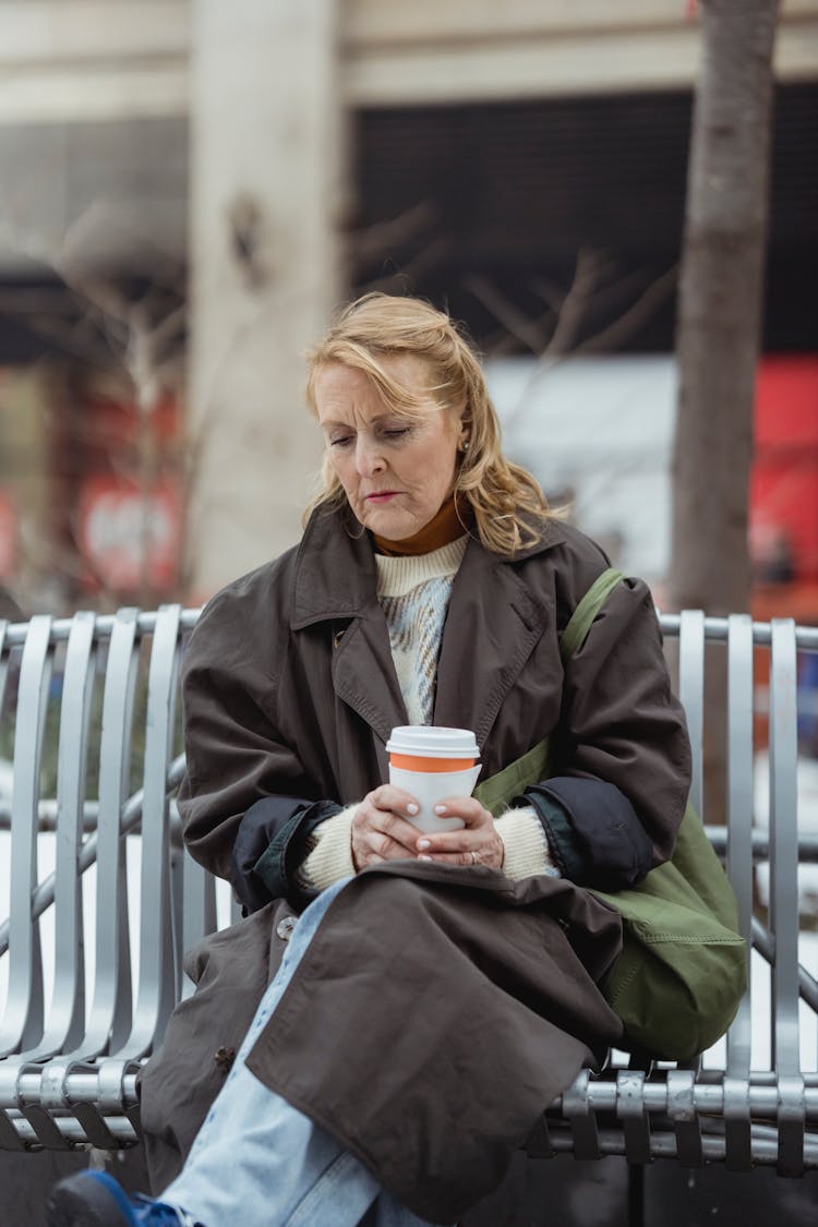 Melancholic Woman With Takeaway Coffee On Urban Bench