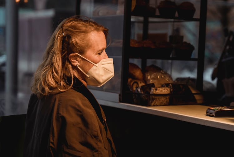 Customer In Respiratory Mask Against Bakery Counter