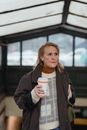 Elderly woman with takeaway coffee in building