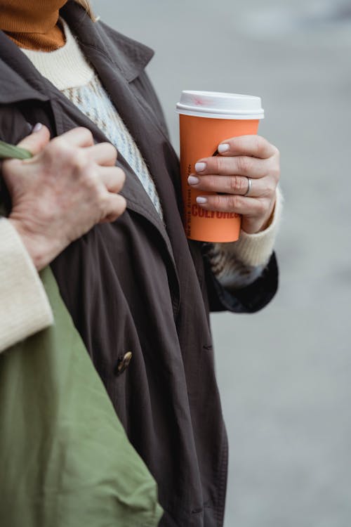 Crop woman with takeaway coffee on street