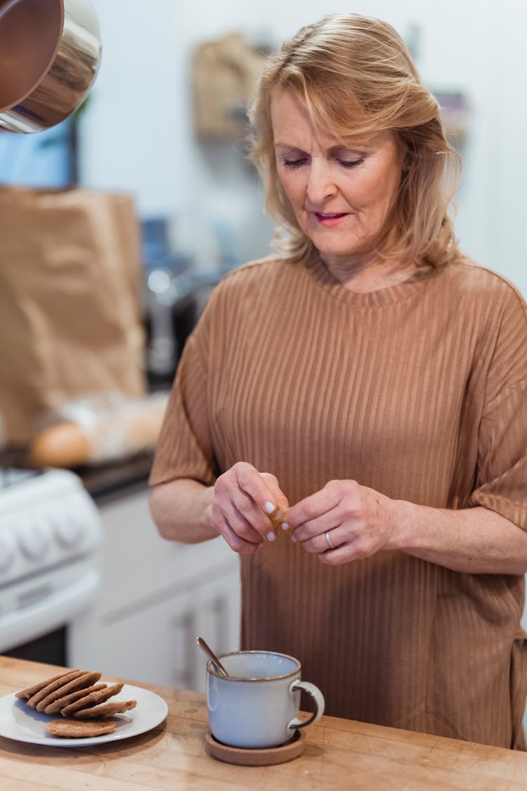 Senior Woman With Cane Sugar Above Mug In Kitchen