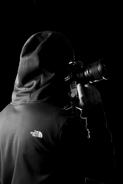 Person in Hoodie Holding Black Camera