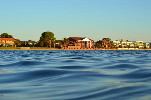 Stunning lakefront homes in West Lakes, Australia, with calm water and a clear blue sky.