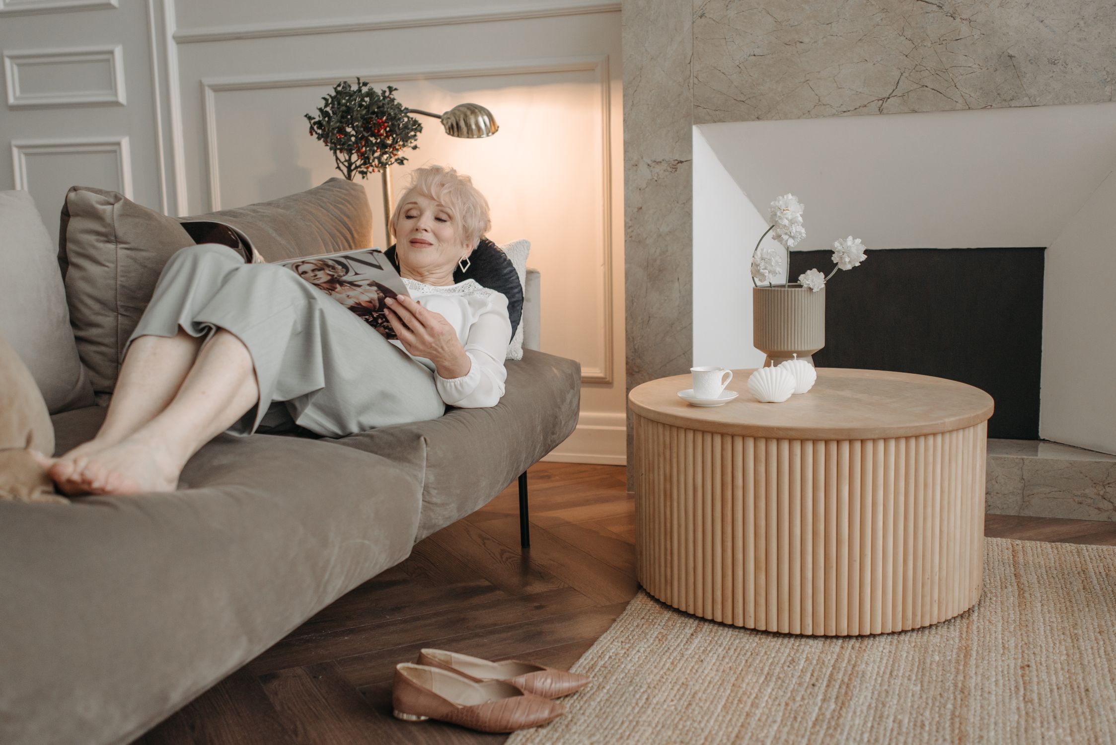 Elderly woman enjoying a magazine on a comfortable sofa in a modern living room.