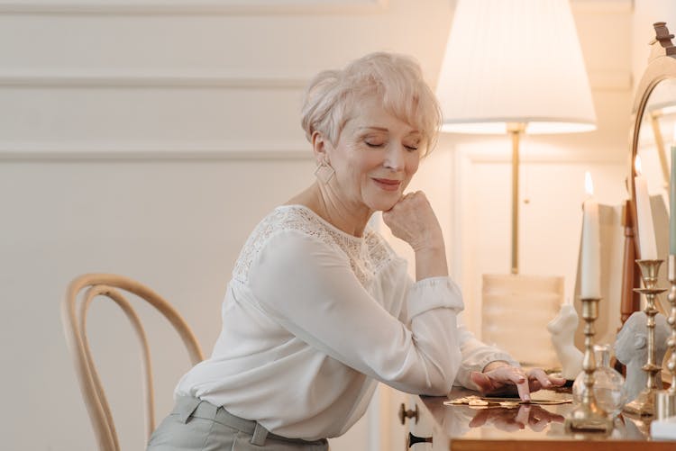 An Elferly Woman Leaning On A Dresser