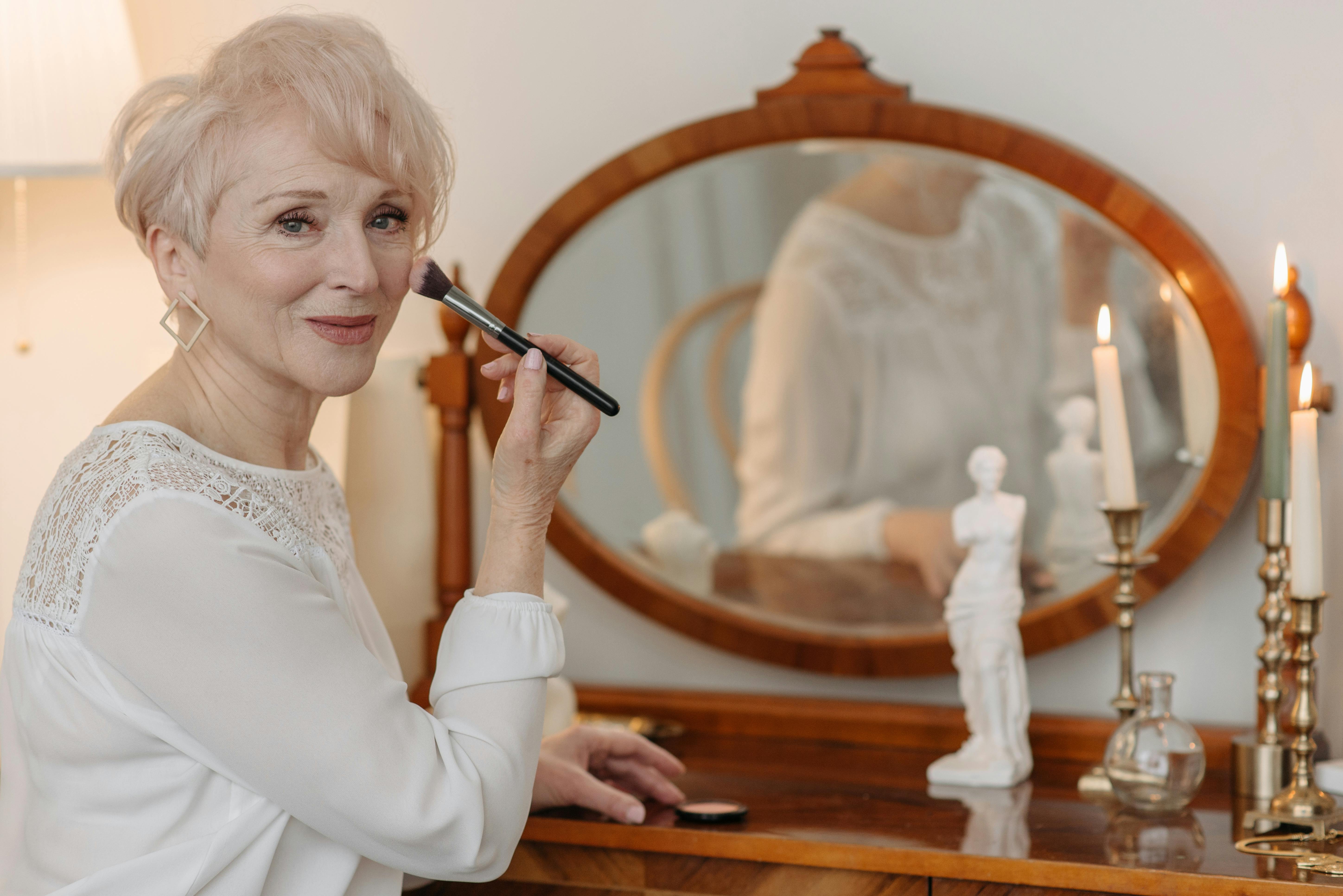 photo of an elderly person putting makeup on her cheek