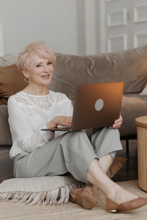 Free Senior woman with laptop smiling indoors, embracing technology and lifestyle. Stock Photo