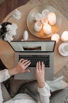 Top view of a person working on a laptop surrounded by candles, embodying a cozy remote work atmosphere.