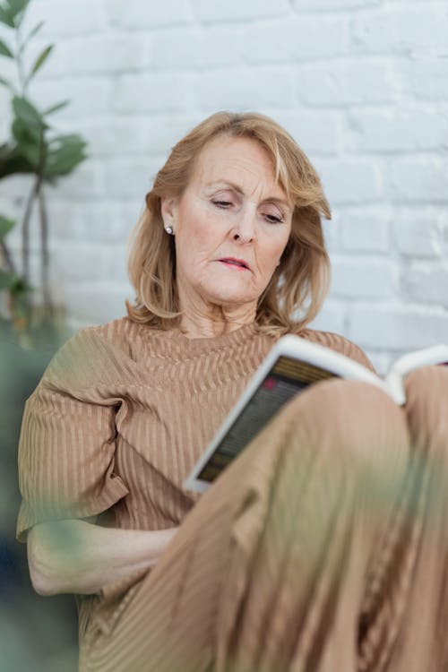 Concentrated elderly woman reading interesting novel at home